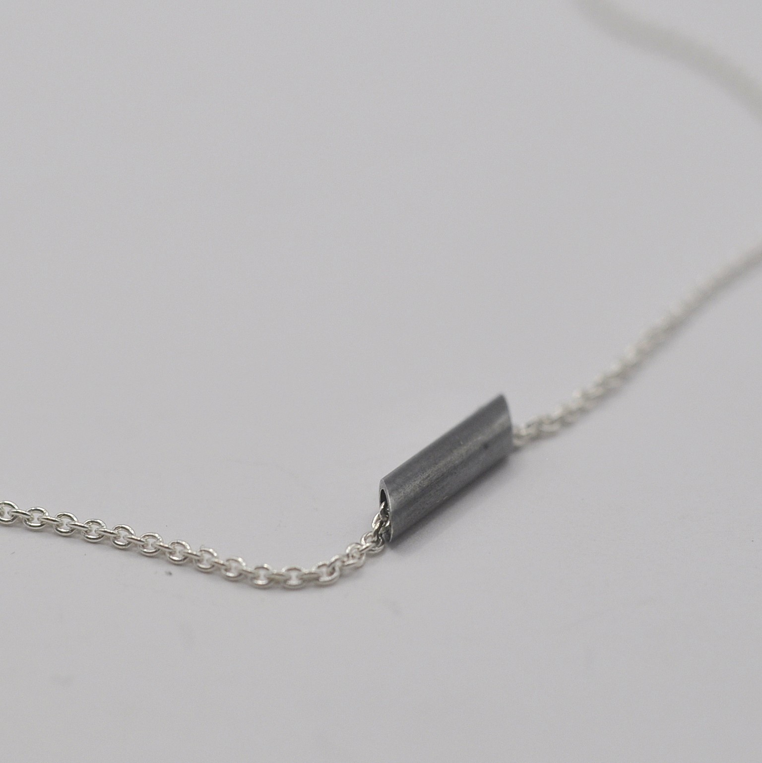 Silberne Kette mit geschwärztem Anhänger in Form eines abgeschrägten Rohrs