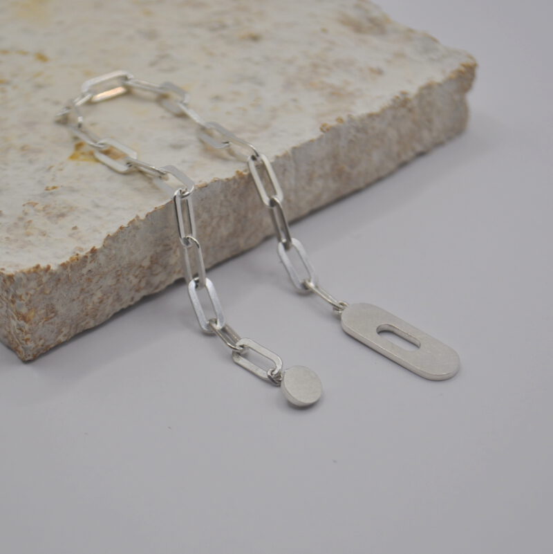 Geöffnetes Armband aus Silber mit ovalem Verschluss liegt auf einer Platte
