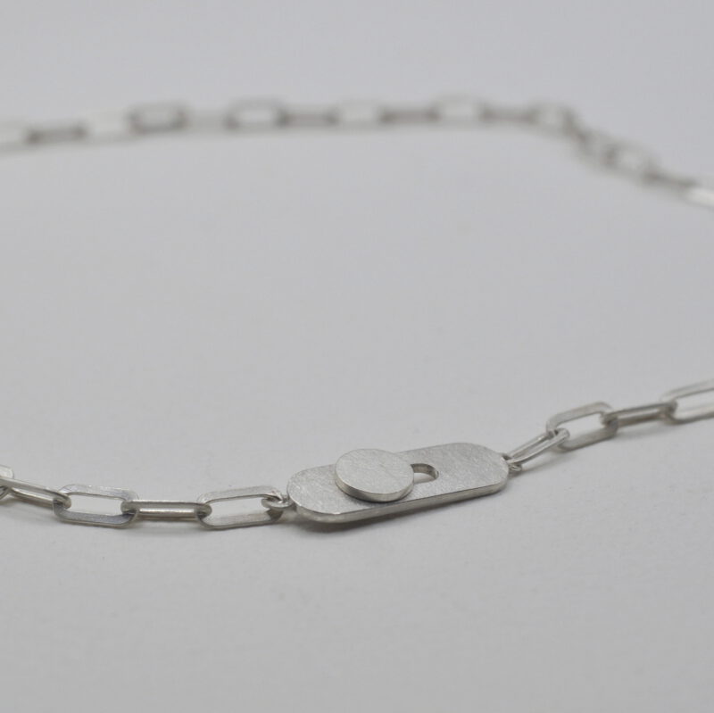 Nahaufnahme einer silbernen Kette mit Knopflochverschluss