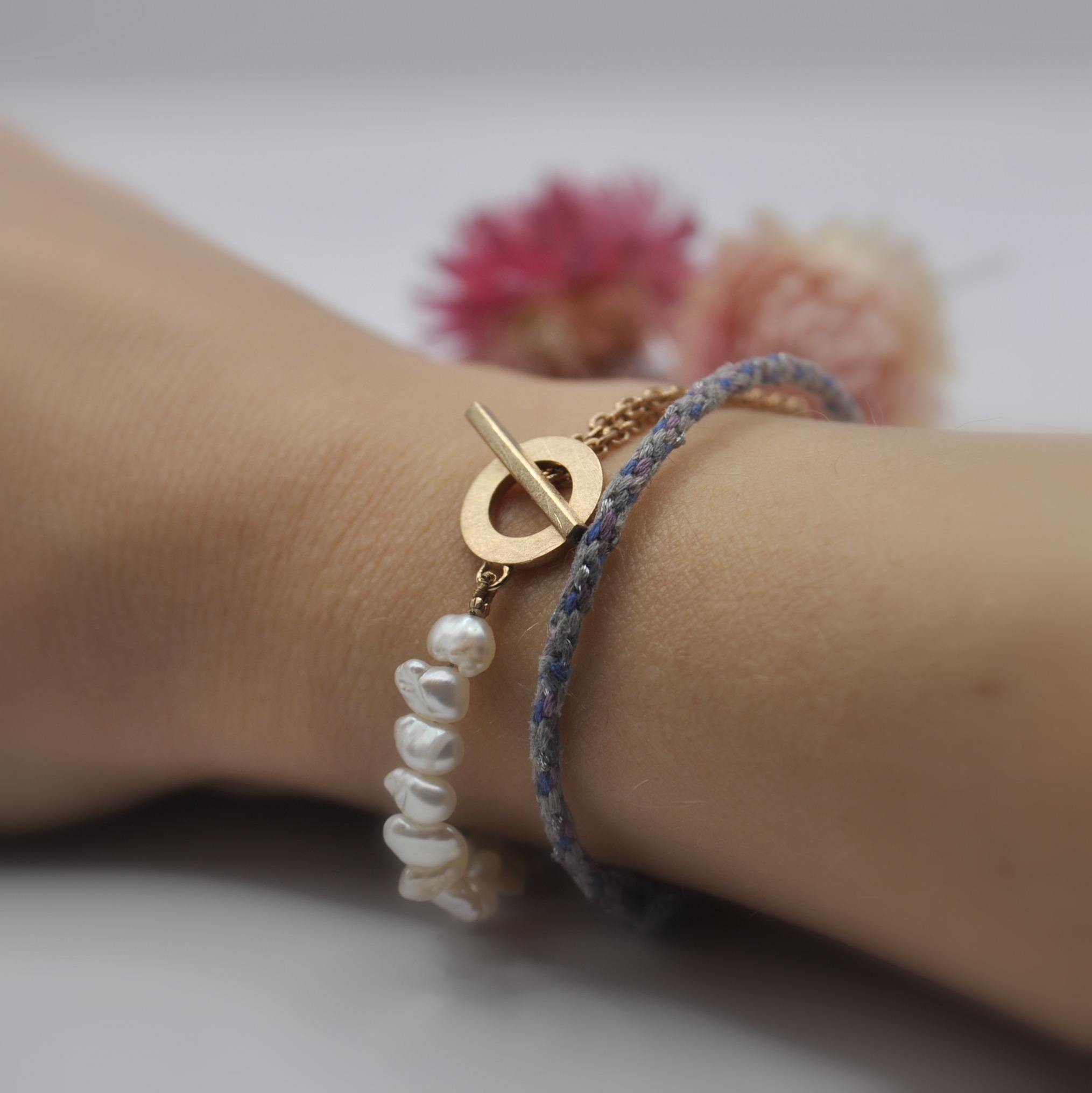 Armband, halb aus quer gebohrten, Süßwasserperlen und halb aus einer rotvergoldeten Ankerkette. Getragen am Arm