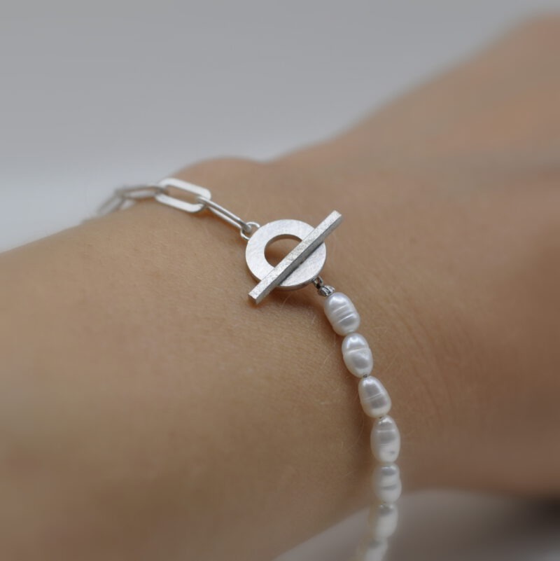 Armband aus Perlen und Silberner Kette an einem Arm