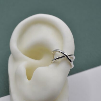 Earcuff aus zwei gekreuzten Runddrähten aus Silber an einem weißen Silikonohr