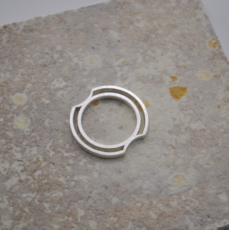 Ring aus Silber, bestehend aus einem Innenring und einem Außenring und Einkerbungen für die Finger