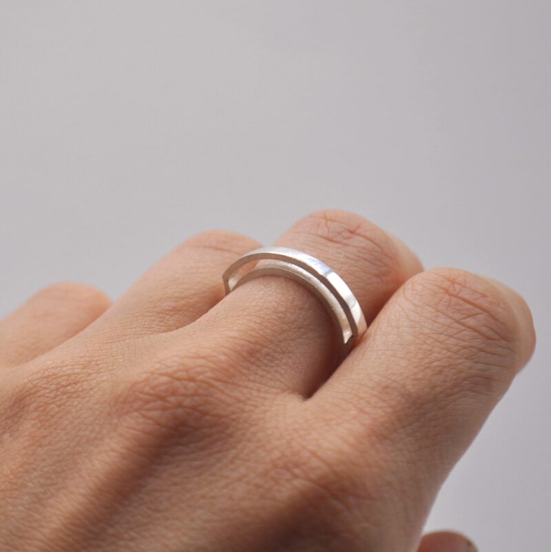 Hand mit Ring "Kanalisiert" Der Außenring umschwebt den Innenring