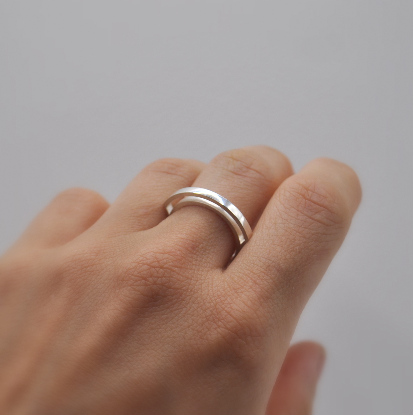 Ring "Kanalisiert" an der Hand. Zwei Ringe, schwebend verbunden.