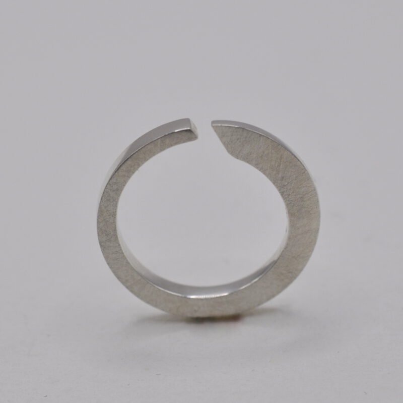 Querschnittsverformter Ring mit schräger Öffnung aus Silber steht aufrecht