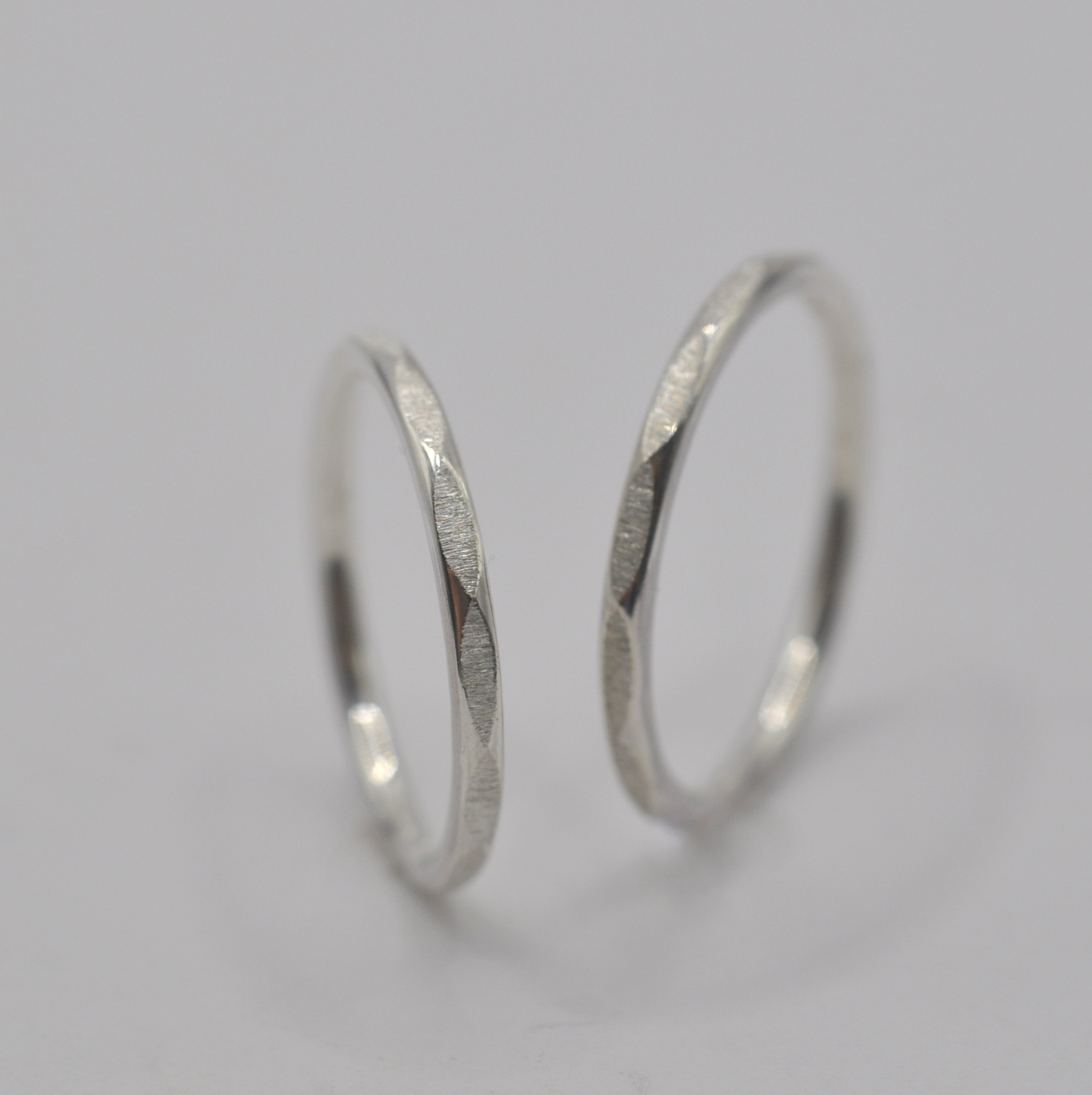 Zwei zarte Silberringe mit feinen Facetten stehen aufrecht