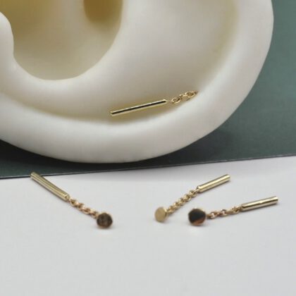 Minimalistische Ohrringe aus Gold. Stabketten mit kleinen Plättchen an einem Silikonohr