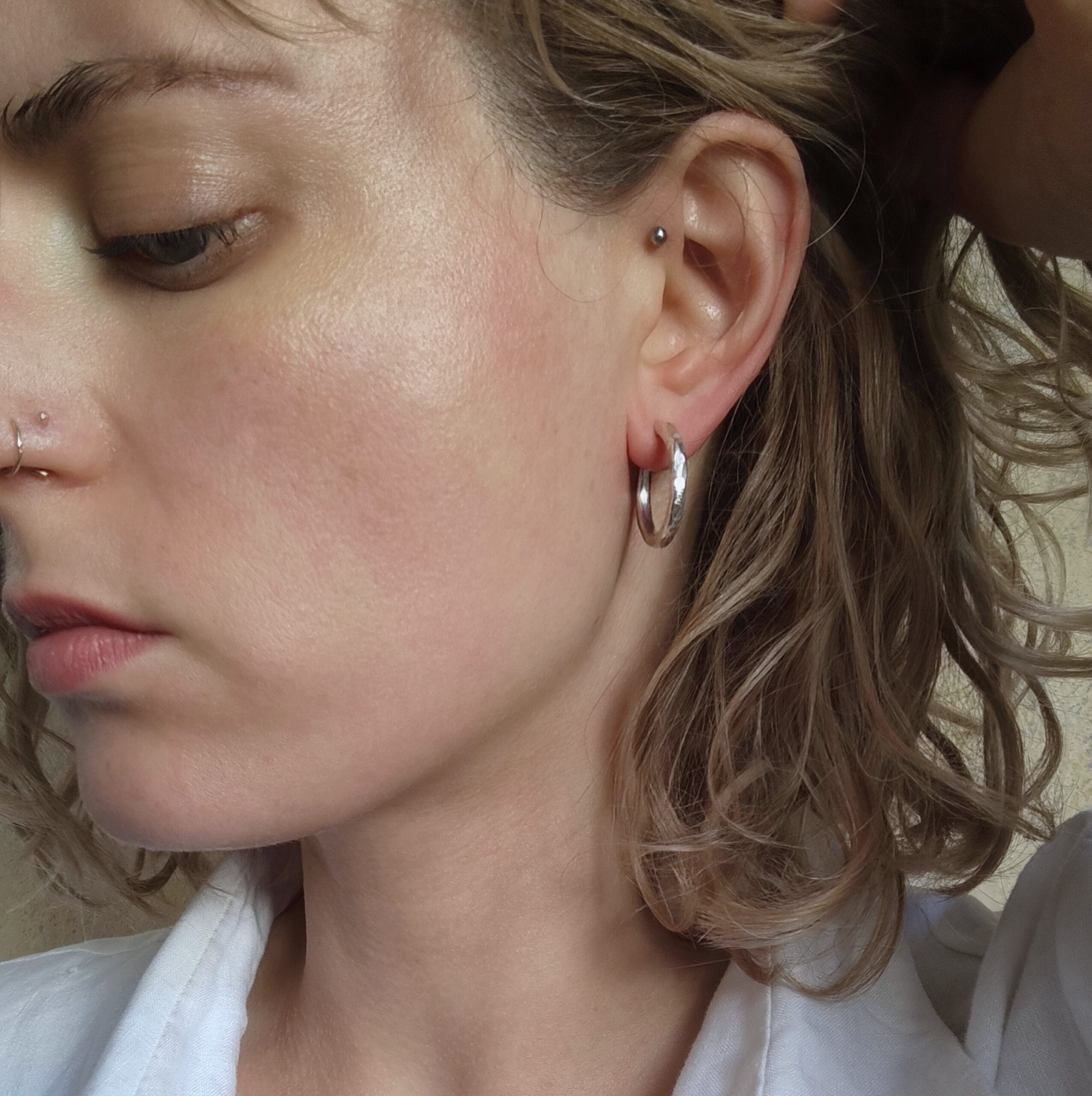 Porträt einer Frau von der Seite, mit Fokus auf silberne Creolen mit gehämmerter Struktur