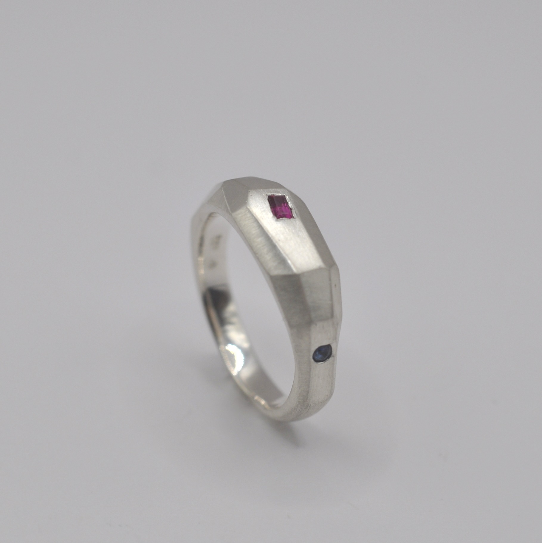 Ring "Erstarrt" mit Flächen und Facetten. Ein eingefasster Rubin und ein Saphir.